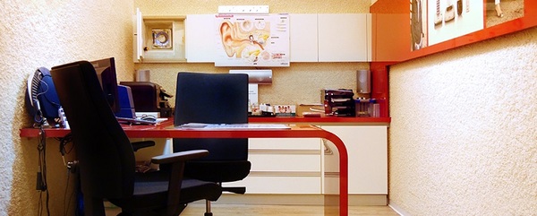 Modernes HNO-Arztpraxis-Büro mit Schreibtisch, Stühlen und Ohr-Poster an der Wand.